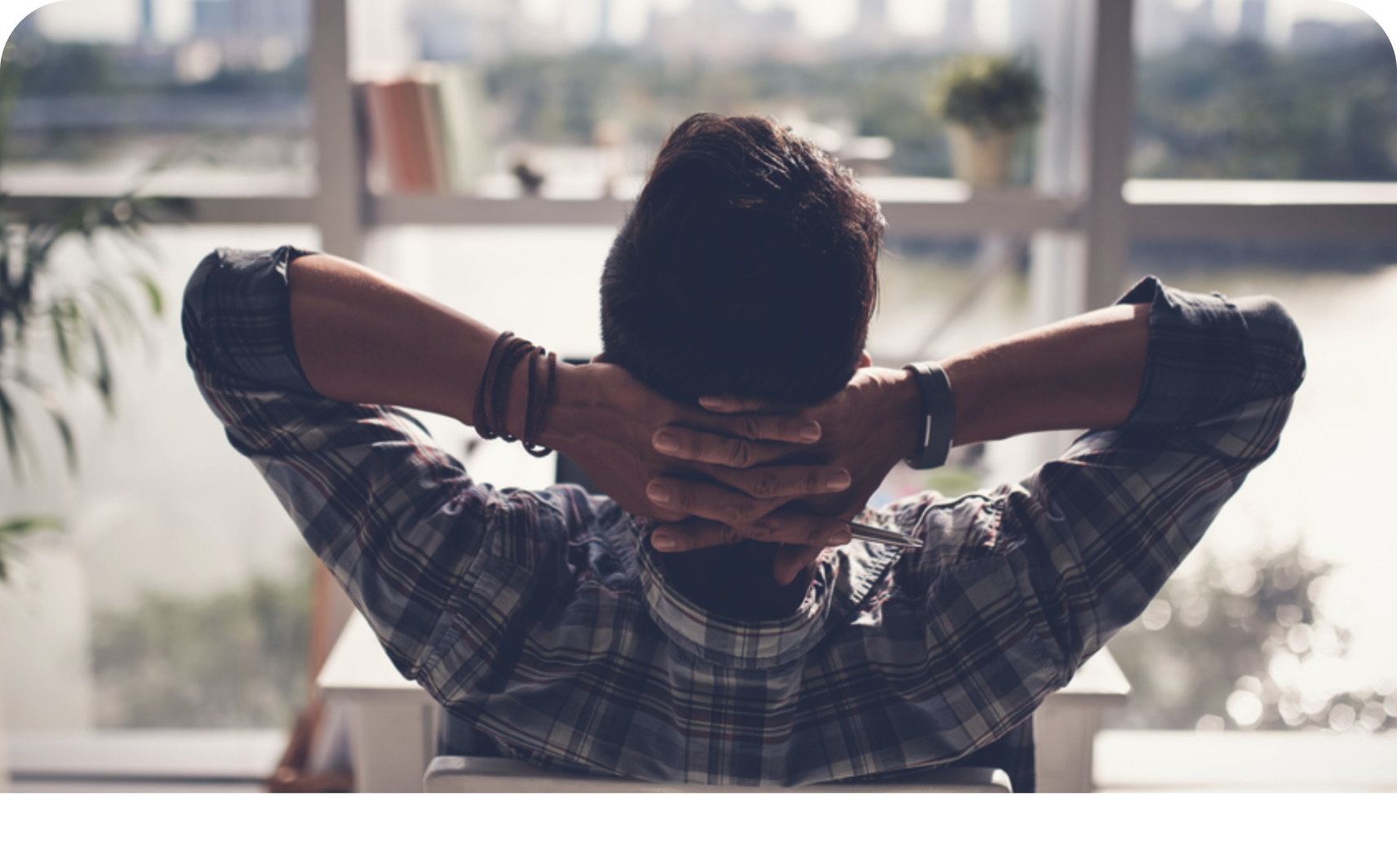 A person leans back at their desk and looks out of the window